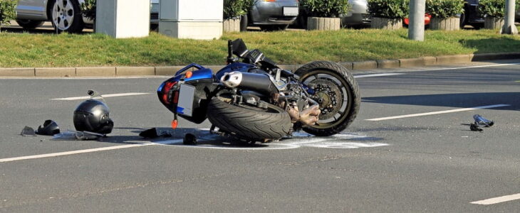 Blue Motorcycle Laying On The Road Next To A Helmet