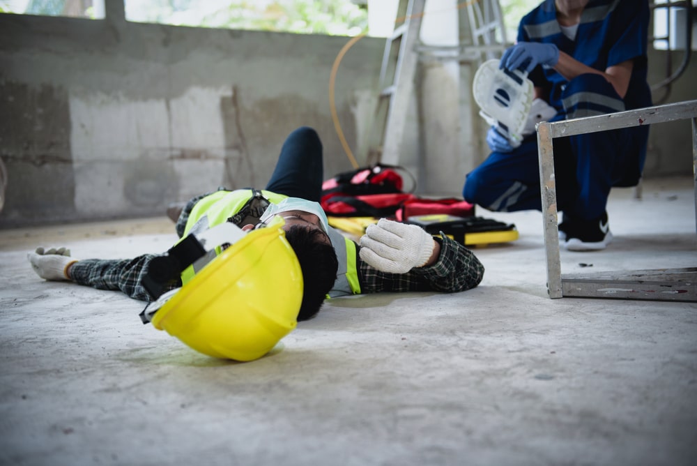 Construction Worker Laying On The Floor Next To Yellow Helmet